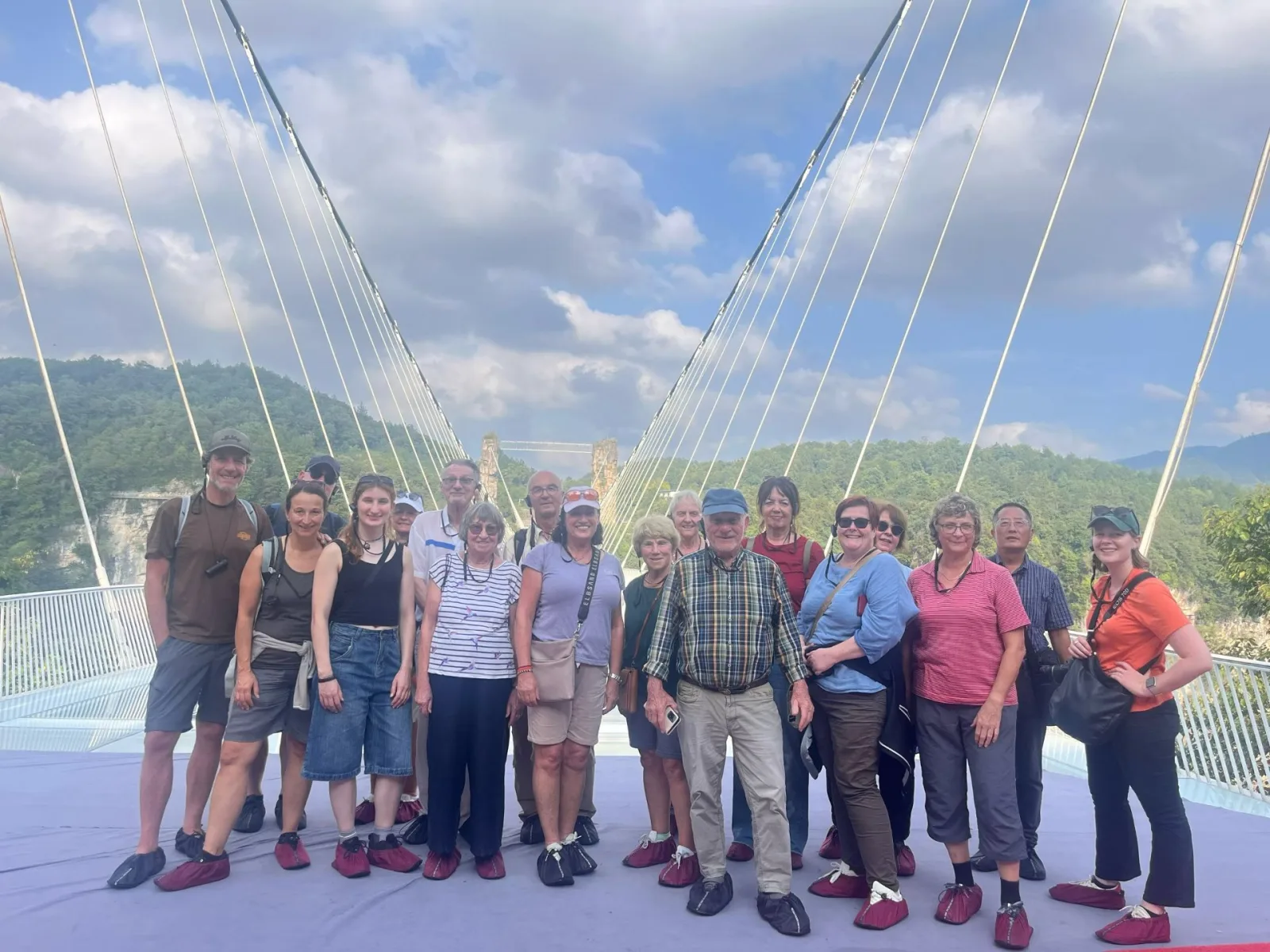 Tour group wearing red shoe covers on the glass bridge at Zhangjiajie Grand Canyon